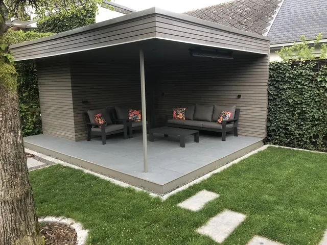 Abri de jardin ouvert à toit plat et bardage gris, salon d'extérieur