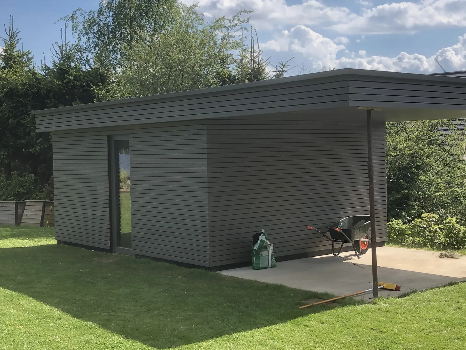 Annexe de jardin bardée de lattes grises avec auvent