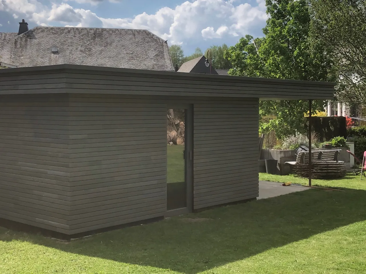 Annexe de jardin à toit plat avec bardage gris et porte vitrée