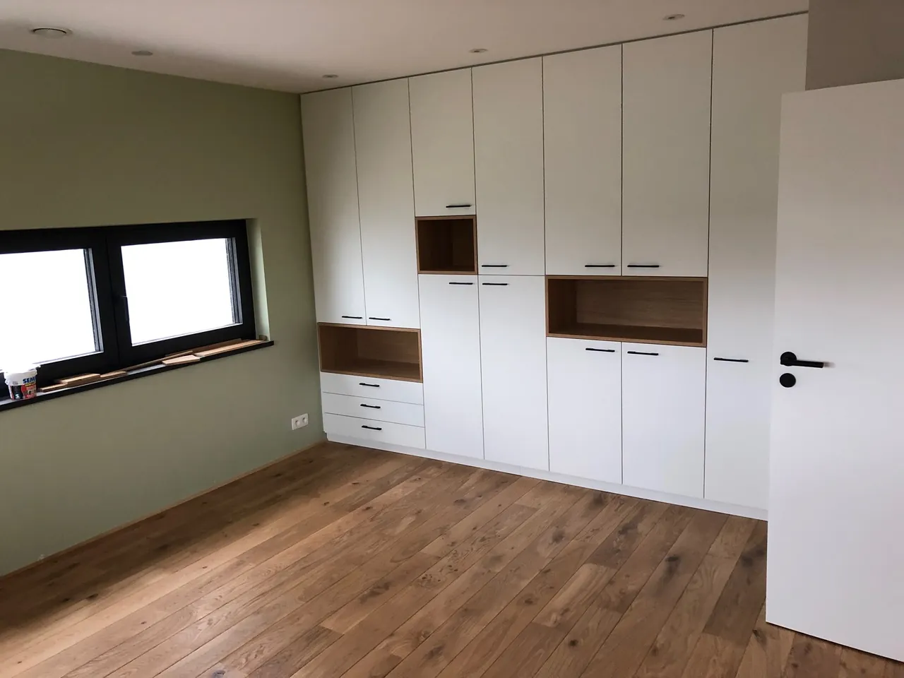 Mur d'armoires blanches encastrées avec niches en bois