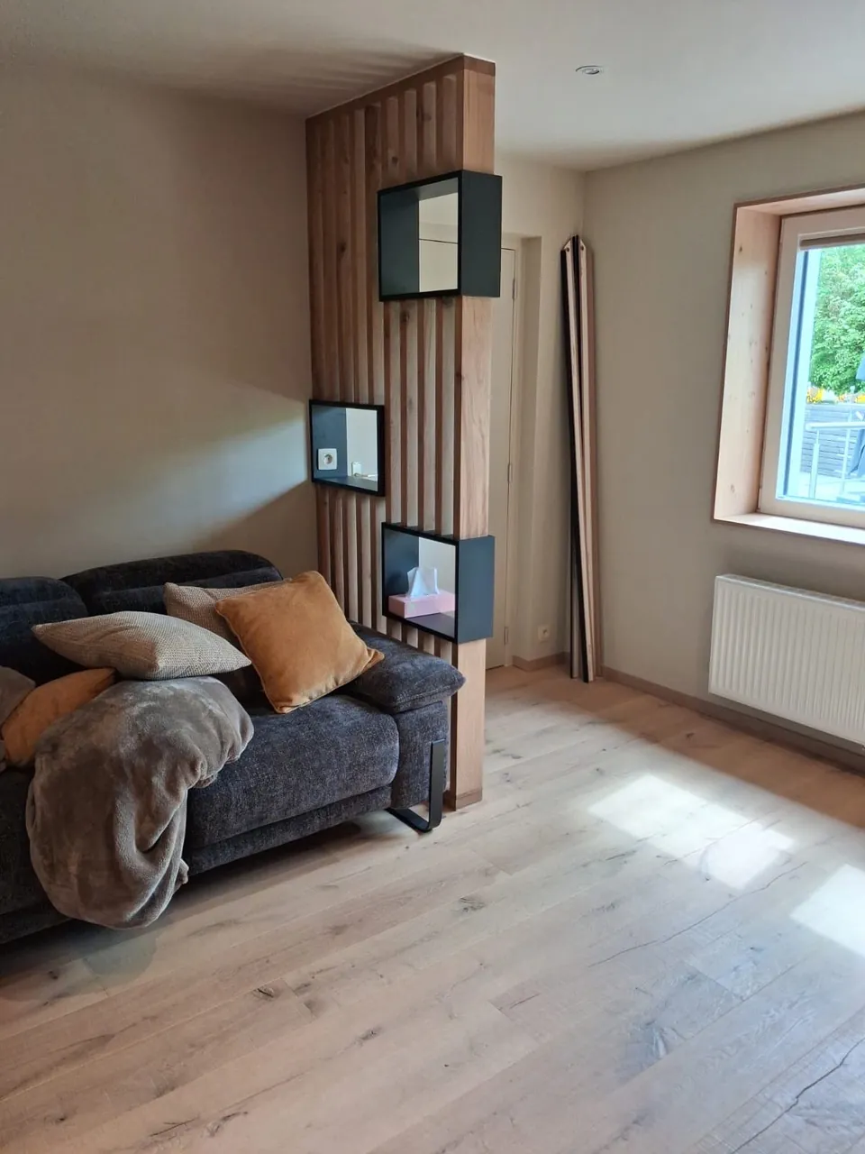 Claustra en lattes de bois avec niches noires dans un salon