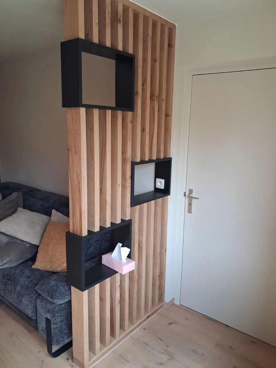 Claustra en lattes de bois et niches noires près d'une porte