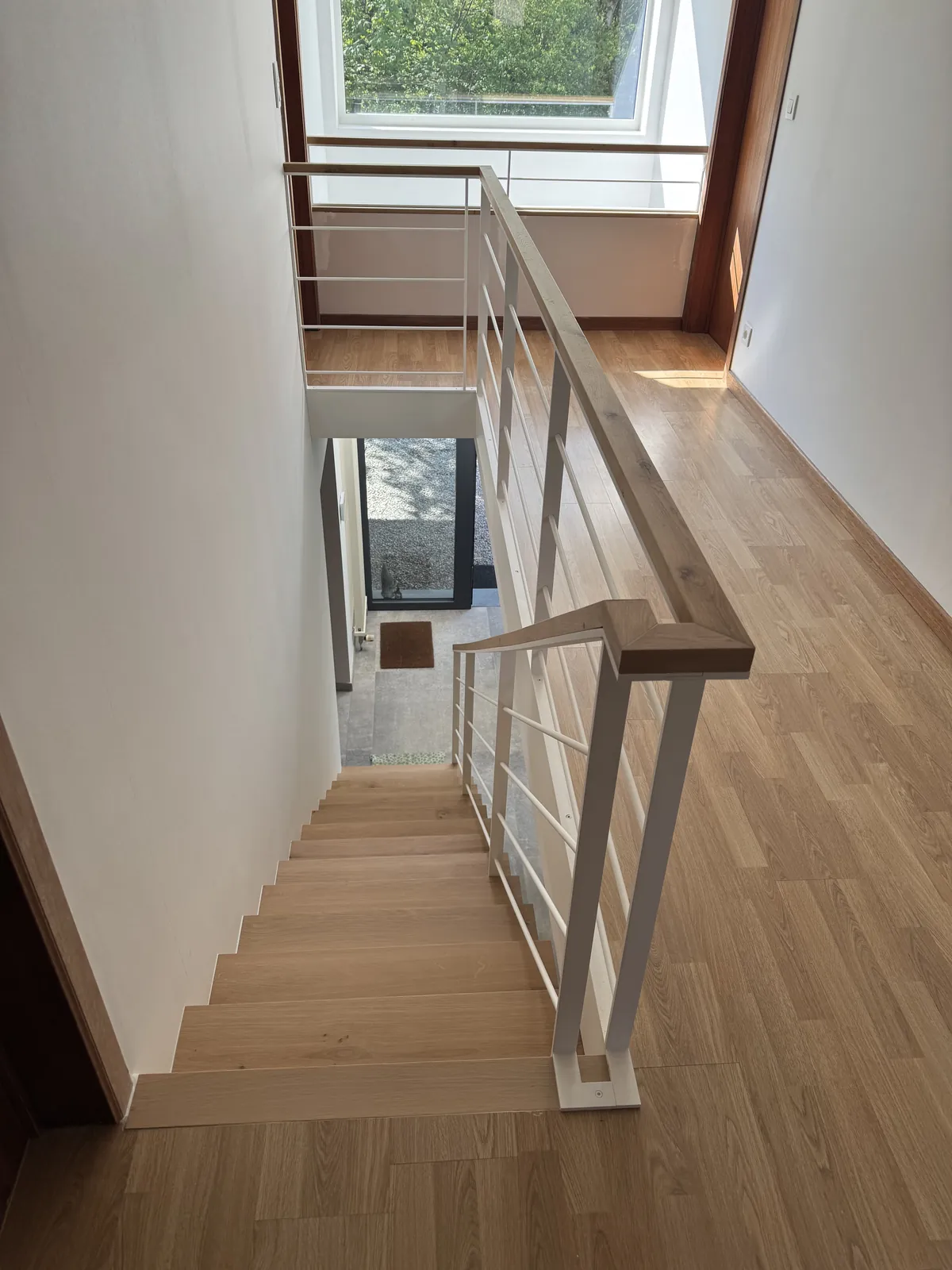Escalier en bois clair avec garde-corps blanc et main courante en bois