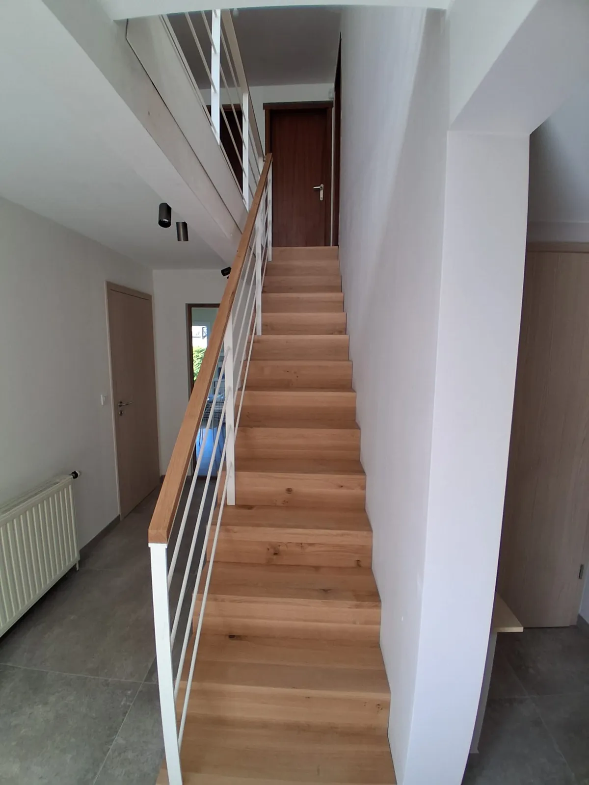 Escalier droit en bois vu du bas, garde-corps blanc