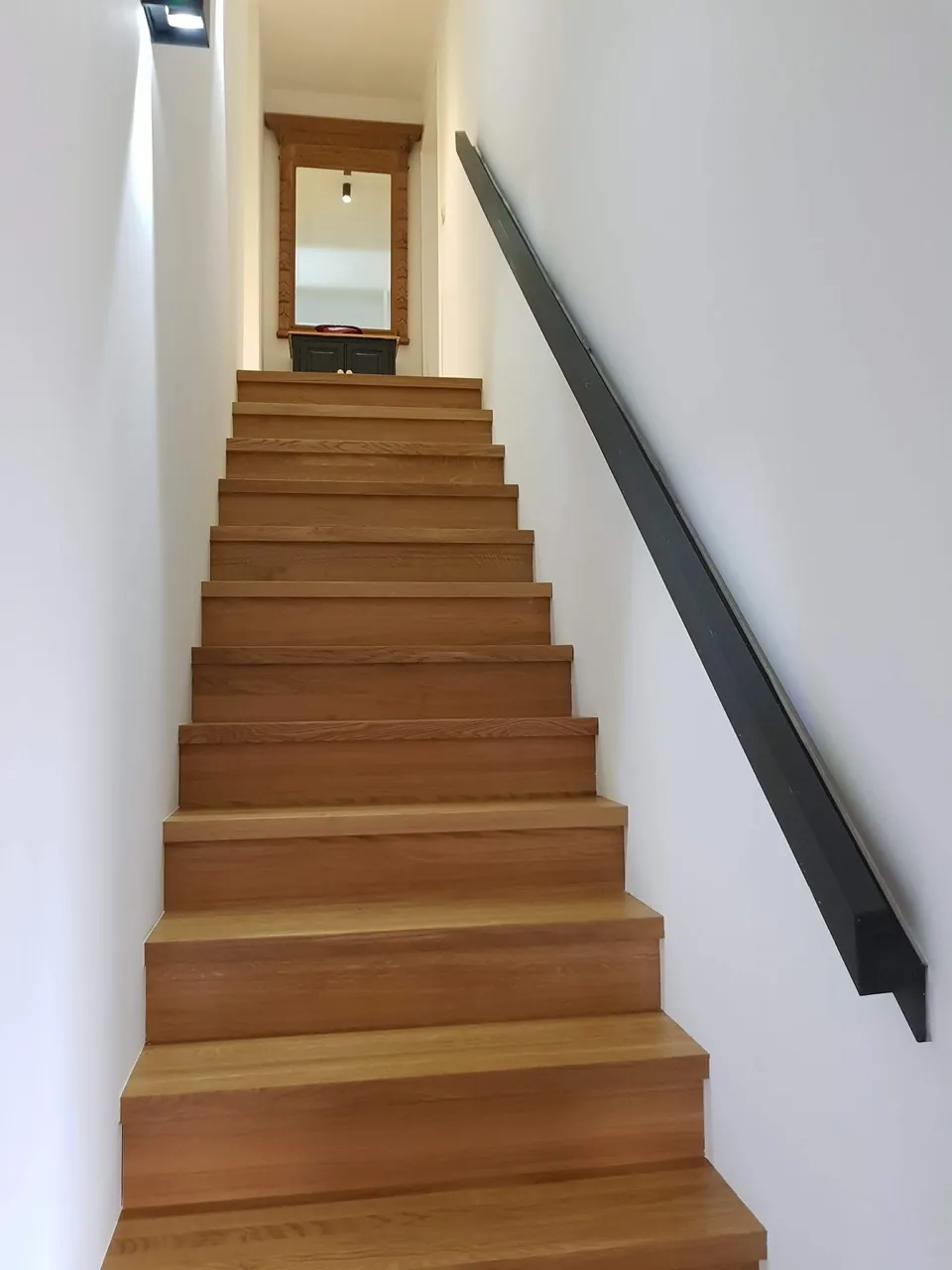 Escalier droit en bois vu de face, main courante noire
