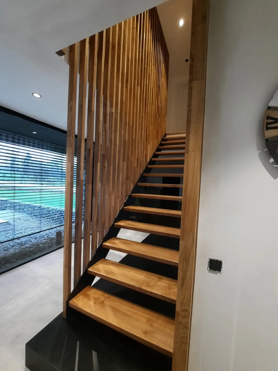 Escalier en bois sur limon noir, claustra et grande baie vitrée