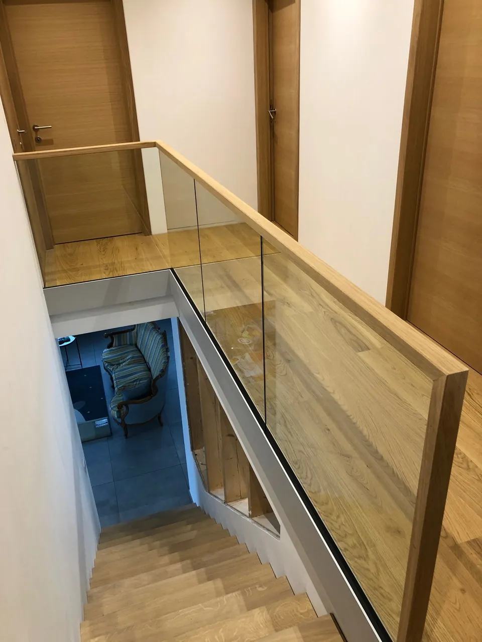 Escalier en bois vu d'en haut derrière un garde-corps en verre