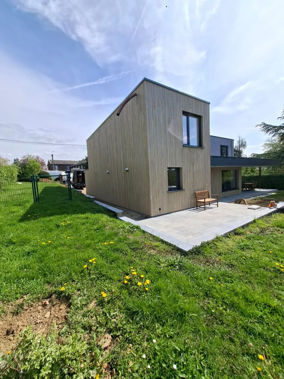 Maison habillée d'un bardage vertical en bois clair, avec terrasse en dalles