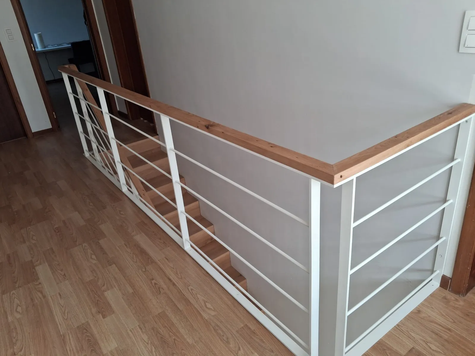 Garde-corps blanc d'angle avec main courante en bois autour de la trémie