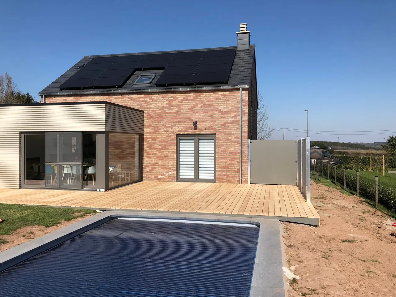Terrasse en bois autour d'une extension bardée, avec piscine